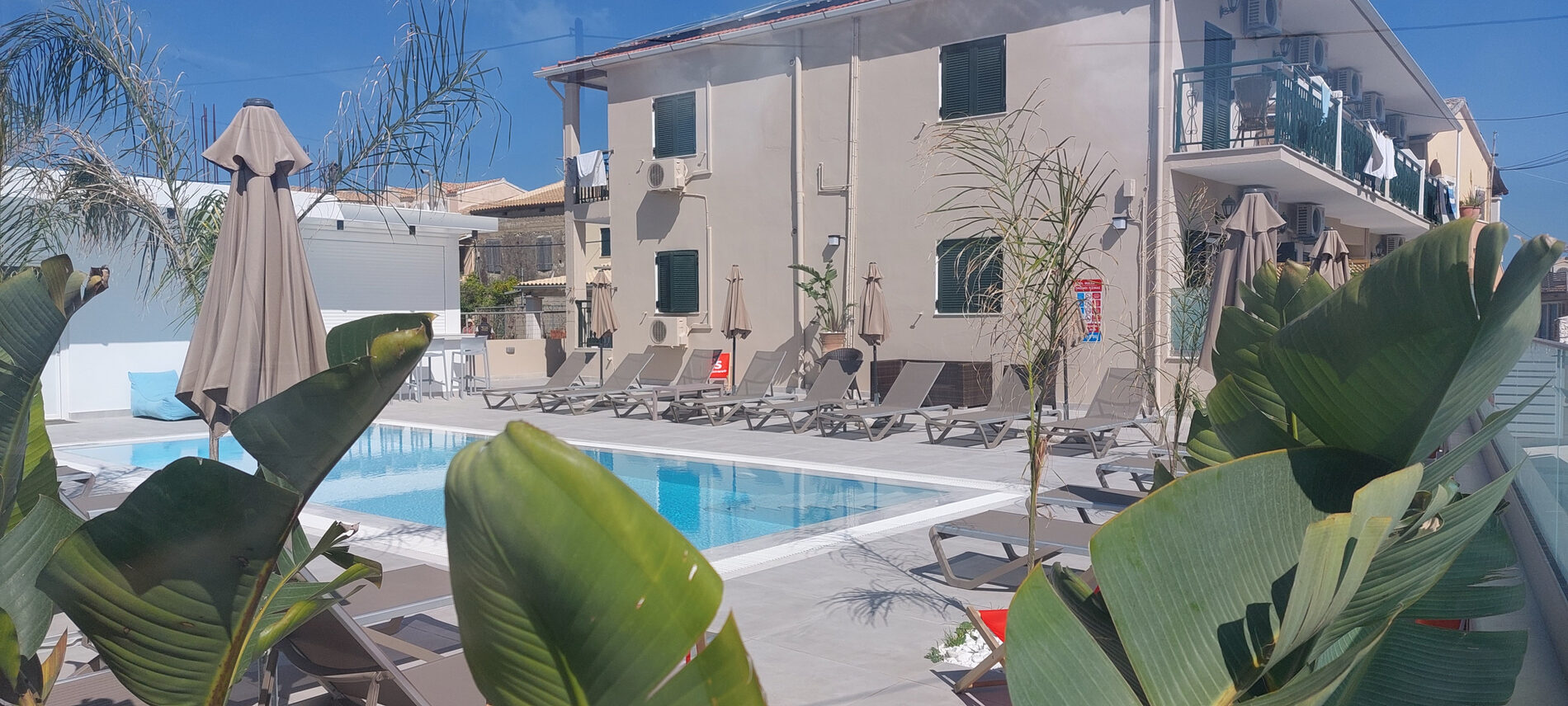 The swimming pool at Ippocrates Apartments with the building behind it