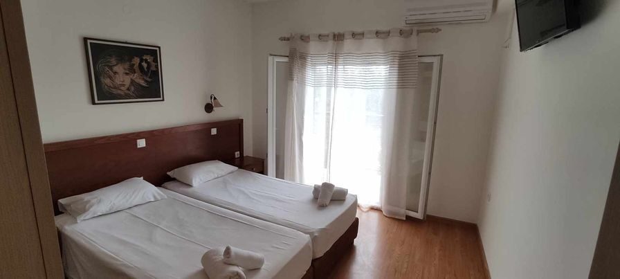 A twin room with wooden floor and balcony doors