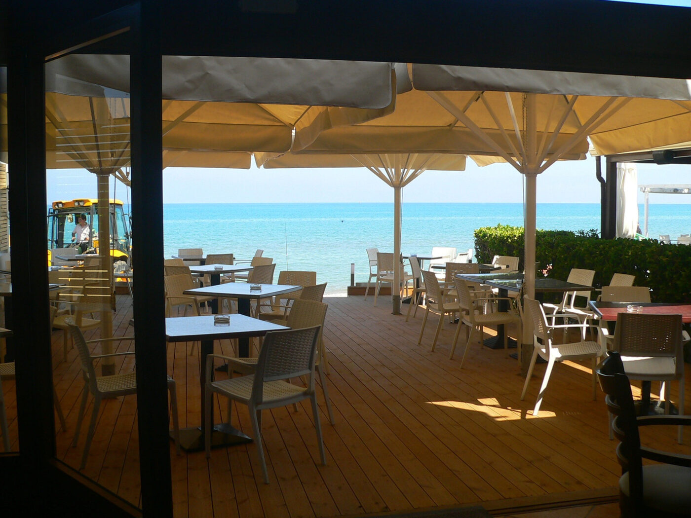 Wooden deck with tables under the shade, the sea beyond